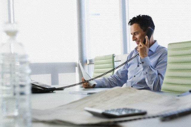 Businessman using telephone while reviewing paperwork.